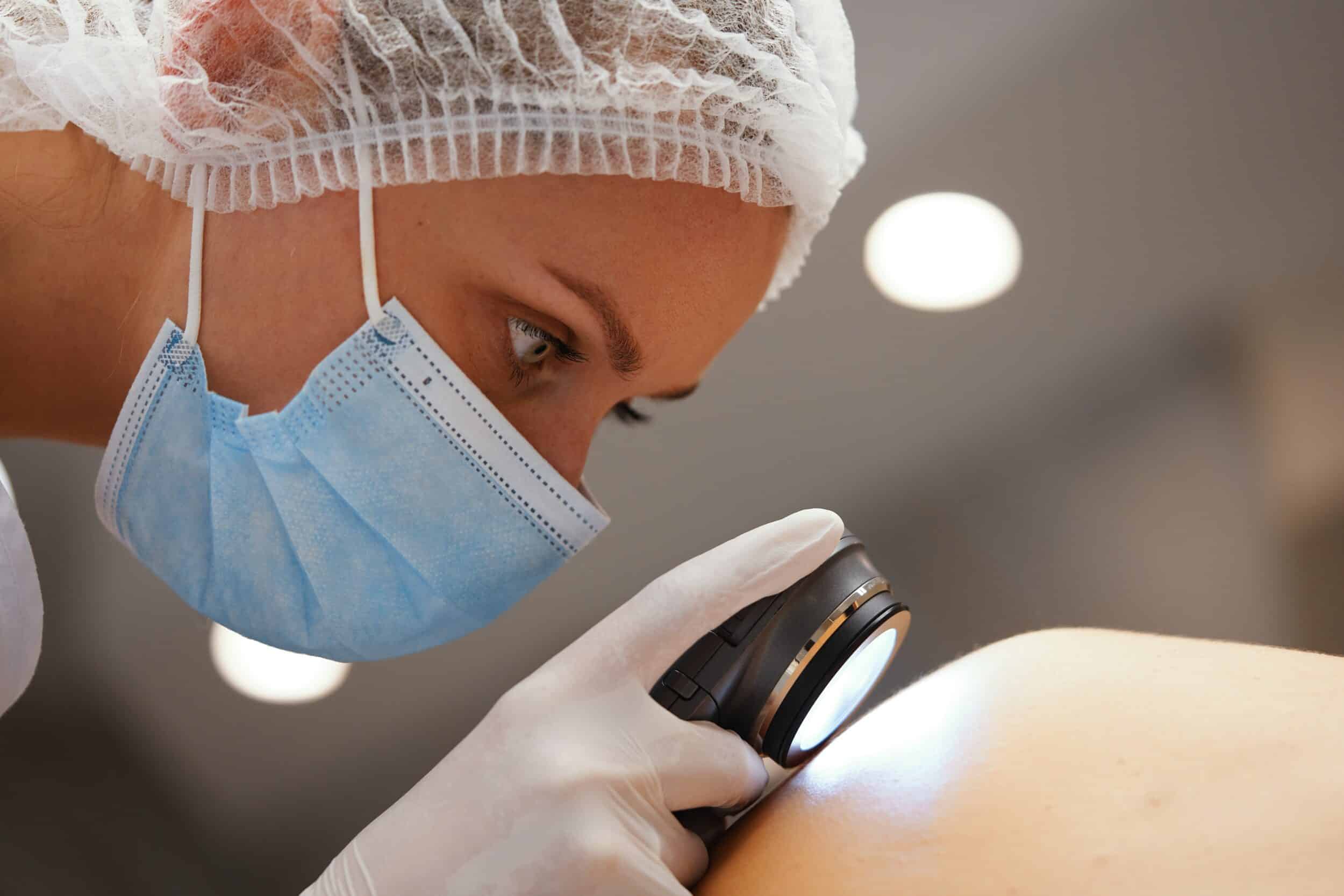 Dermatologist closely examining a patient's skin during a professional skin check in a clinical setting