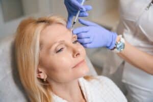 Close-up of woman receiving anti-wrinkle injection from cosmetologist during facial rejuvenation procedure